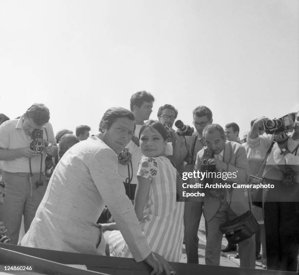 Italian actor Marcello Mastroianni with the swedish actress Anna Karina while sitting on a boat, surrounded by photographers, in Venice for the Movie...