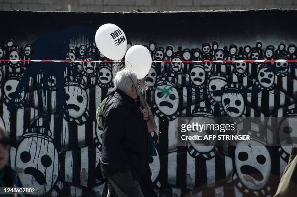 Participants hold balloons reading "Never Again" as they walk towards the old railway station in Thessaloniki, on March 19 while taking part in a...