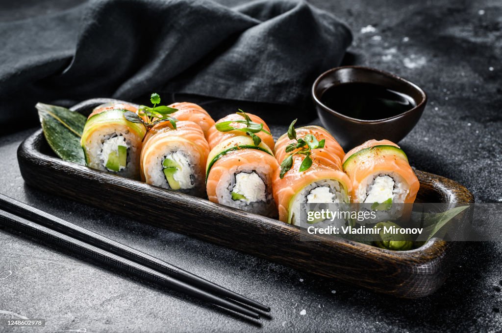 Sushi roll Philadelphia with salmon, avocado, cream cheese. Sushi menu. Japanese food. Black background. Top view