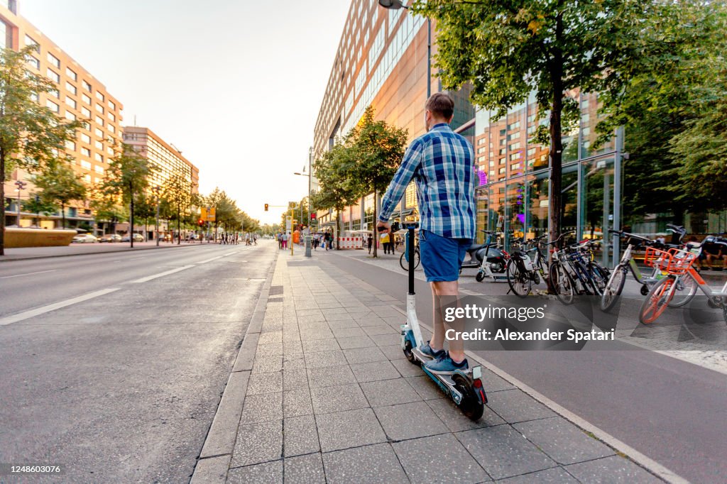 Man riding on electric push scooter on the streets of Berlin, Germany