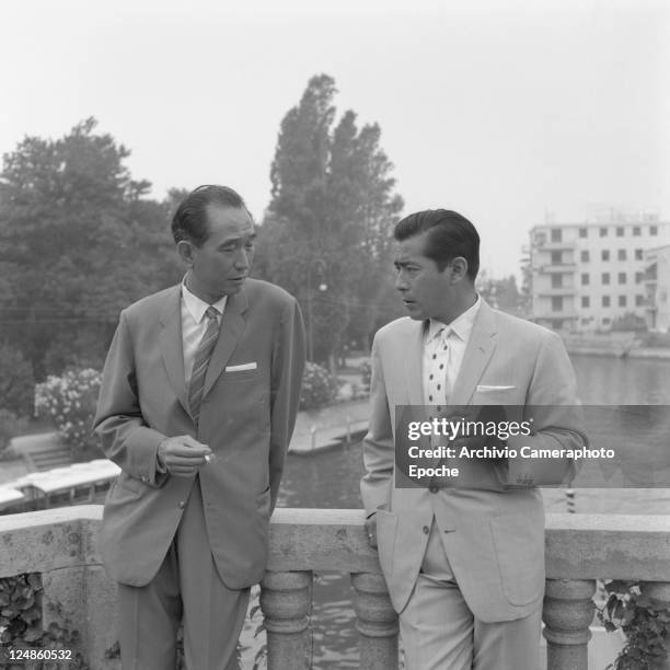 Japanese director Akira Kurosawa , wearing a suit and a striped tie, portrayed while smoking a cigarette with the japanese actor Toshiro Mifune,...