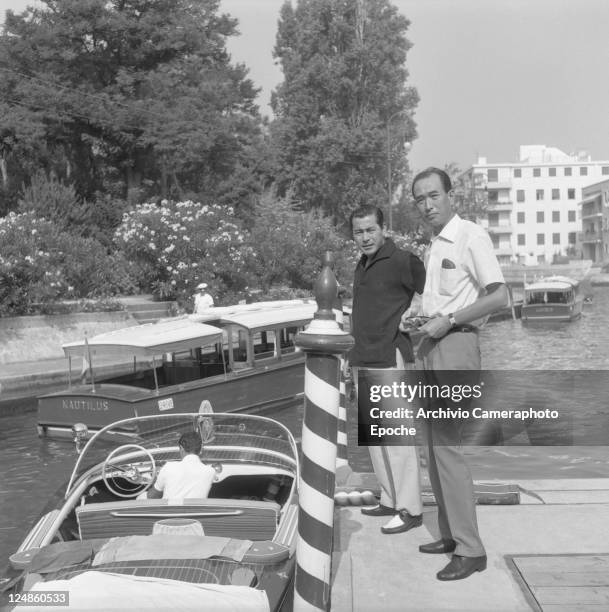 Japanese director Akira Kurosawa portrayed with the japanese actor Toshiro Mifune while waiting to go on board of a water taxi berthed nearby,...