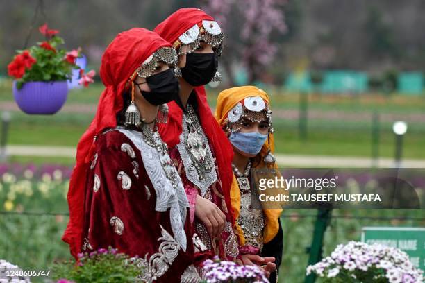Women wearing traditional Kashmiri dress walk at the Tulip garden in Srinagar on March 19, 2023.