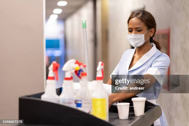 sirvienta trabajando en un hotel haciendo servicio de habitaciones usando una máscara facial y empujando un carro - criada fotografías e imágenes de stock