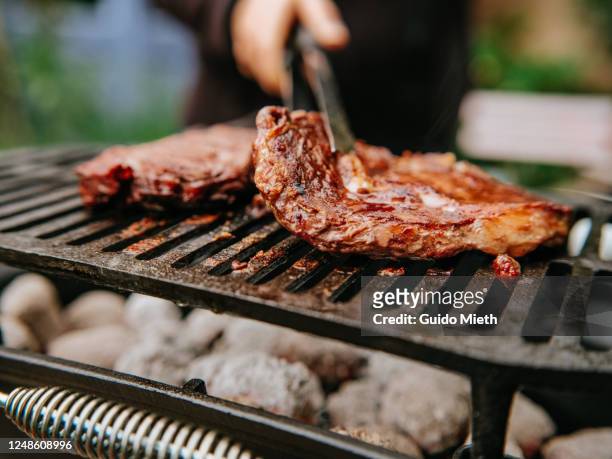 woman doing bbq steaks on a flame grill. - grill fire meat stockfoto's en -beelden