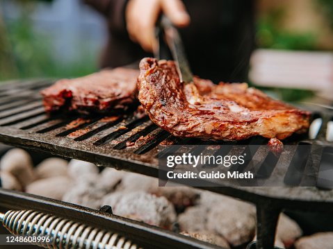 Woman doing BBQ Steaks on a flame grill. Woman doing BBQ Steaks on a flame grill.