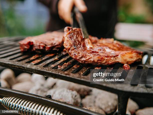 woman doing bbq steaks on a flame grill. - grill stock pictures, royalty-free photos & images