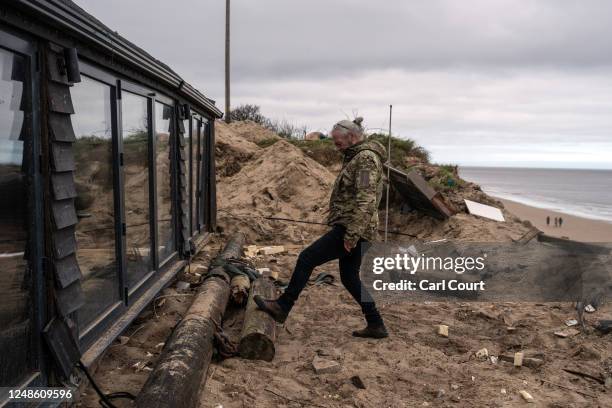 Lance Martin moves a log next to his bungalow after he dragged it around 3 metres inland from the edge of an eroding cliff to avoid a council...