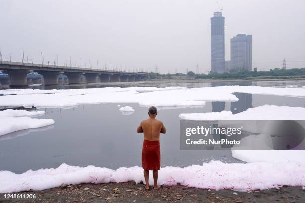 Man performs rituals as he takes a dip in the polluted waters of river Yamuna laden with toxic foam, caused by industrial and domestic discharge,...