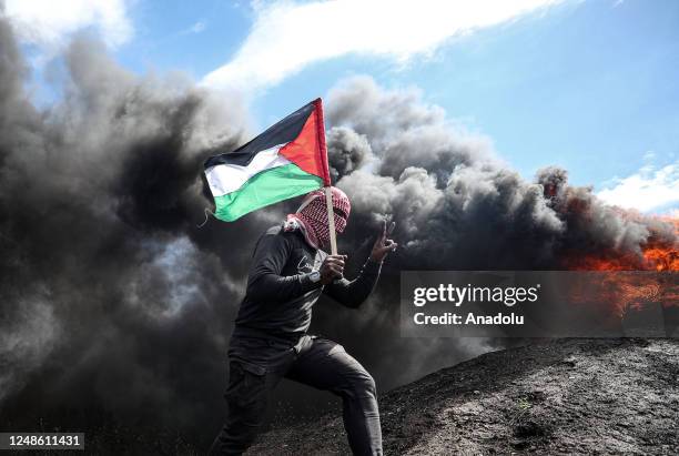 Palestinians holding flags burn tires during a demonstration to protest against the participation of the Palestinian Authority in a planned security...