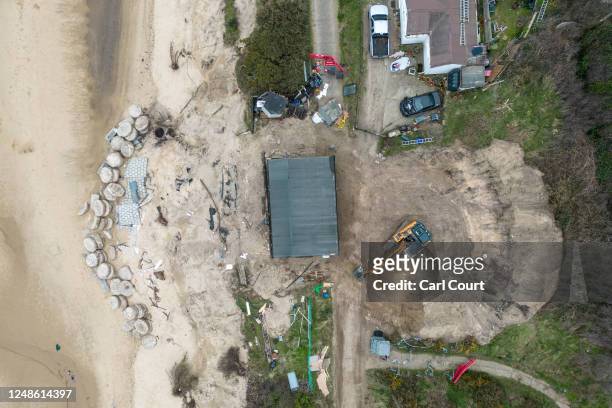 An excavator works to clear land behind a clifftop bungalow after its owner, Lance Martin, moved it around 3 metres inland from the edge of an...