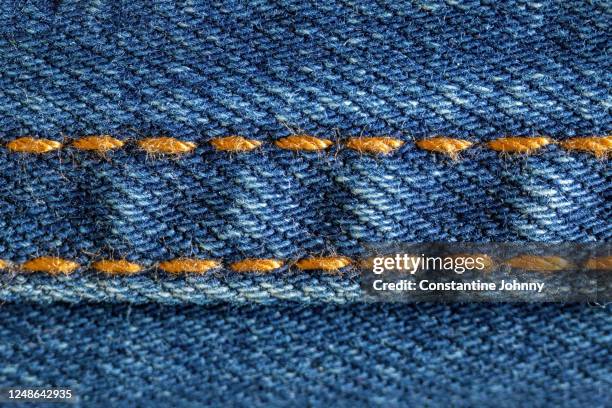 close up of golden stitches on blue denim jeans - costura fotografías e imágenes de stock