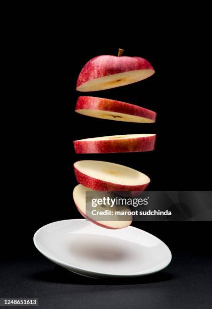 the sliced ​​bright red apples are floating in a white plate in the air - apple slice photos et images de collection