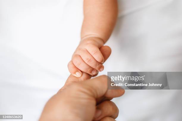 newborn baby holding adult finger - mum dad and baby fotografías e imágenes de stock