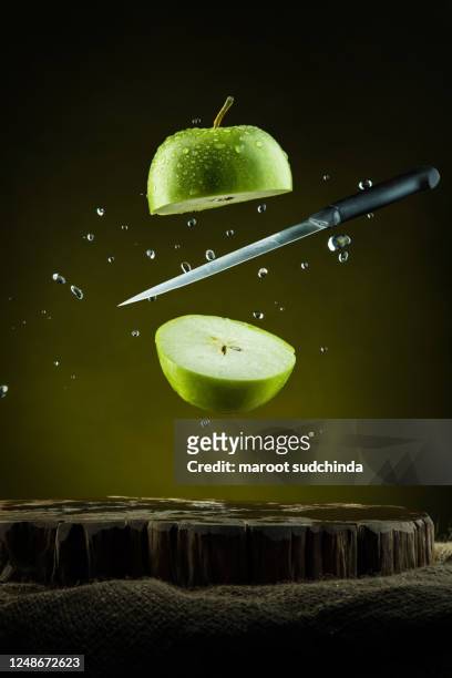 flying slices of green apple with knife - küchenmesser stock-fotos und bilder