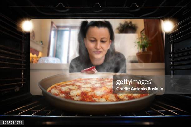 woman taking a pizza out of the oven - hot sauce photos et images de collection