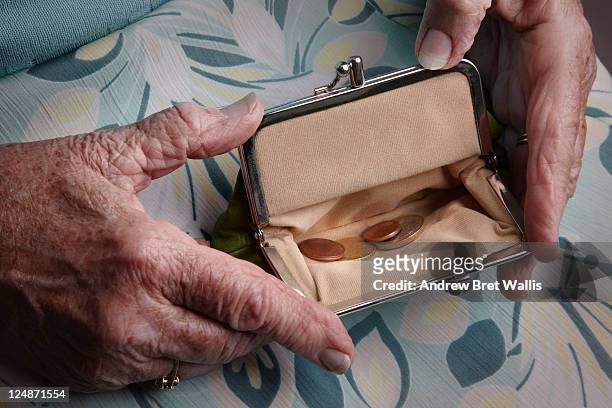senior woman holding open a purse on her lap - pensionamento foto e immagini stock