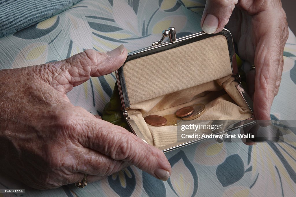 Senior woman holding open a purse on her lap
