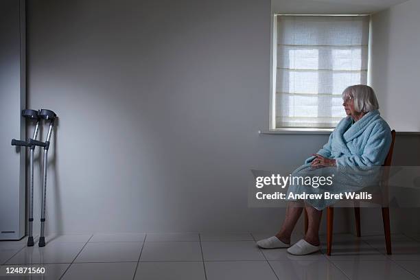 senior woman seated alone out of reach of crutches - lonely senior stock pictures, royalty-free photos & images