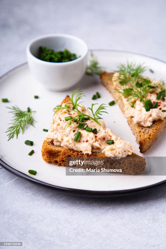 Close up of an open sandwich with salmon pate and some fresh herbs