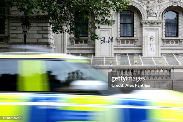 Police car passes graffiti next to Downing Street on June 10, 2020 in London, England. As the British government further relaxes Covid-19 lockdown...