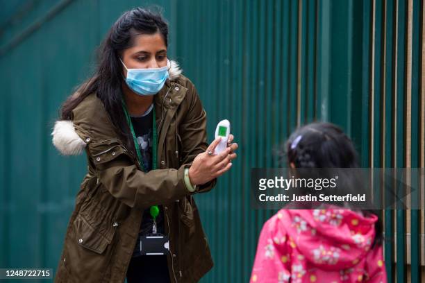 Child has her temperature checked by a teacher before entering Earlham Primary School, which is part of the Eko Trust on June 10, 2020 in London,...
