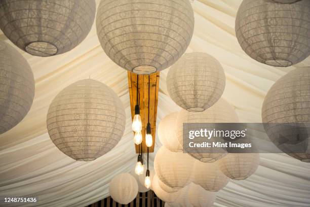 detail of white japanese rice paper lamps and fabric canopy, decorations for a naming ceremony in an historic barn. - japanischer lampion stock-fotos und bilder