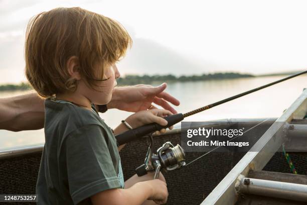 a five year old boy fishing from a boat on the zambezi river, botswana - kids fishing stock pictures, royalty-free photos & images