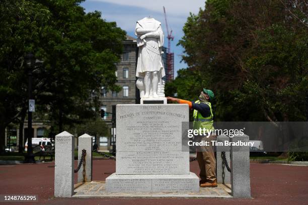 Worker from the Boston Parks & Recreation Department inspects a statue depicting Christopher Columbus which had its head removed at Christopher...