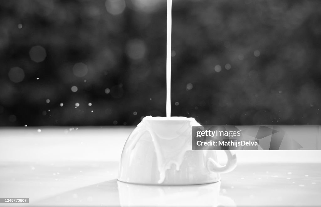 Milk pouring onto an upside down cup