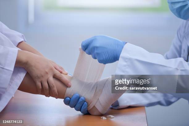 doctor bandaging a patient's foot - ankle sprain stock-fotos und bilder