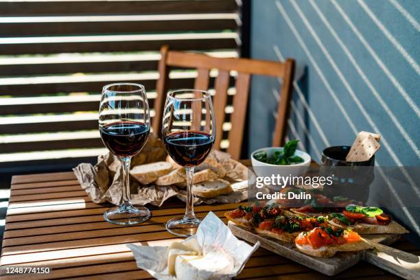 two glasses of red wine with antipasto snacks on a table outdoors - bruschetta stock-fotos und bilder