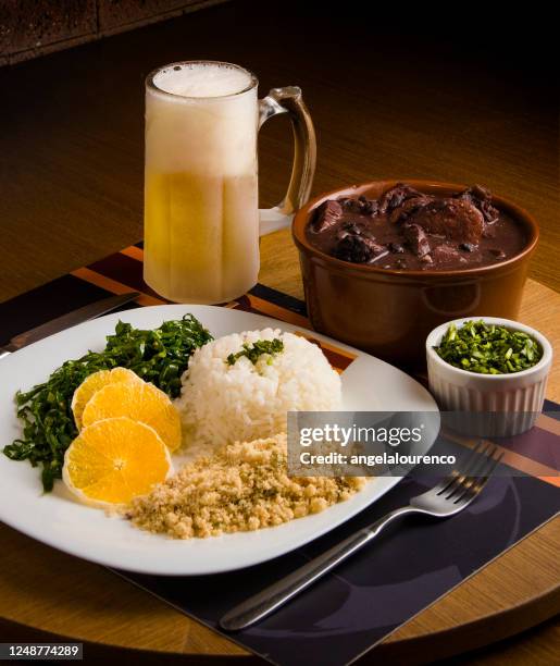feijoada stew with farofa, rice, kale and a glass of beer - brazilian feijoada dish stock-fotos und bilder