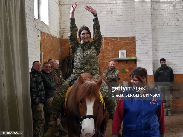 Ukrainian servicewoman rides a horse during a hippotherapy session in Kyiv on March 17, 2023. - In a cosy barn on the outskirts of Kyiv, a group of...