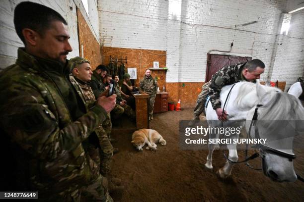 Ukrainian serviceman rides a horse during a hippotherapy session in Kyiv on March 17, 2023. - In a cosy barn on the outskirts of Kyiv, a group of...