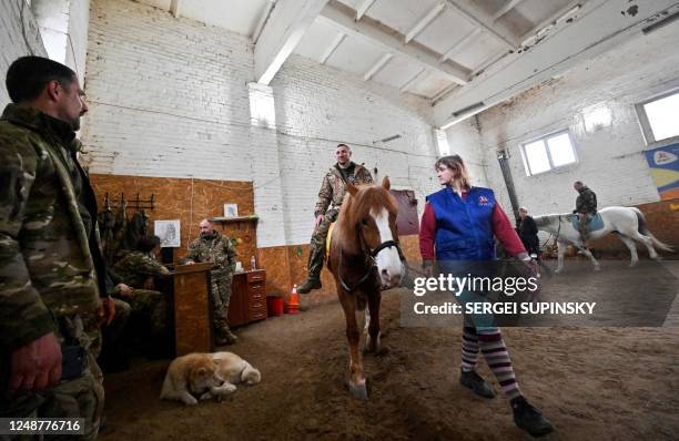 Ukrainian serviceman rides a horse during a hippotherapy session in Kyiv on March 17, 2023. - In a cosy barn on the outskirts of Kyiv, a group of...