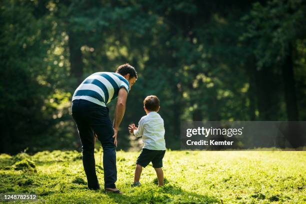 glücklicher vater spricht mit seinem sohn im freien - beugen oder biegen stock-fotos und bilder