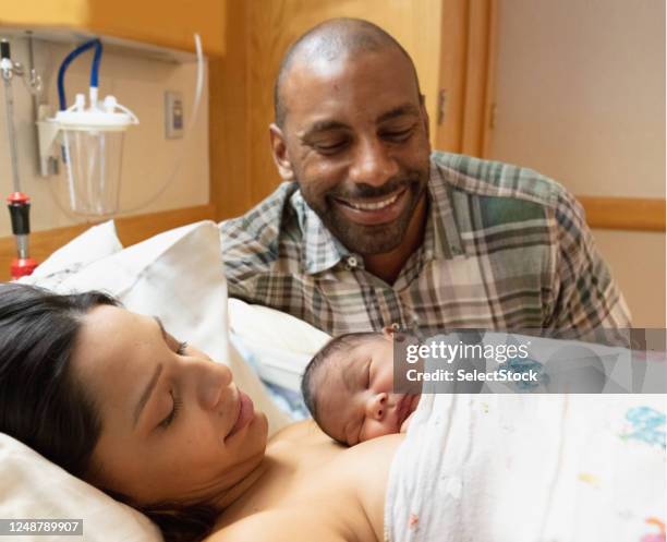 mixed race family admiring their newborn baby at hospital with mother - new mother stock pictures, royalty-free photos & images