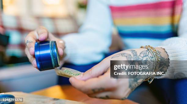 hands of young woman rolling up a joint of marijuana - marijuana tattoo stock pictures, royalty-free photos & images