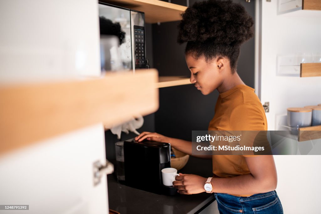 コーヒーメーカーで淹れたてのコーヒーを準備する女性