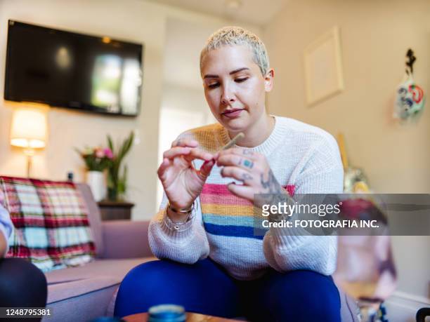 young woman rolling up a joint of marijuana - marijuana tattoo stock pictures, royalty-free photos & images