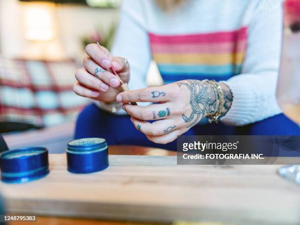 hands of young woman rolling up a joint of marijuana - marijuana tattoo stock pictures, royalty-free photos & images