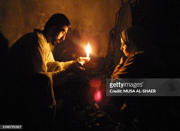 Palestinian couple sit in a candlelit room of their home in the Aida refugee camp 12 March 2002 in the West Bank town of Bethlehem after their house...