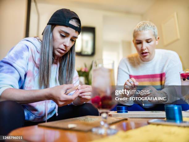 two young women rolling up a joints of marijuana - marijuana tattoo stock pictures, royalty-free photos & images