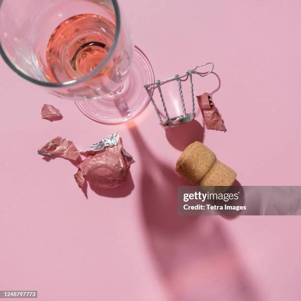 studio shot of champagne cork and wineglass on pink background - tappo di champagne foto e immagini stock