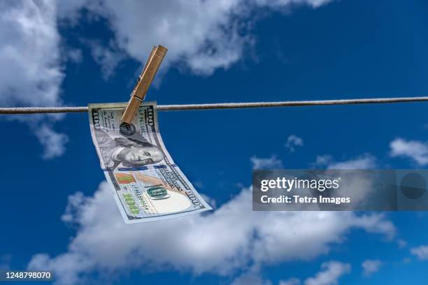 one hundred dollar bill drying on clothesline against sky - money laundering stock pictures, royalty-free photos & images