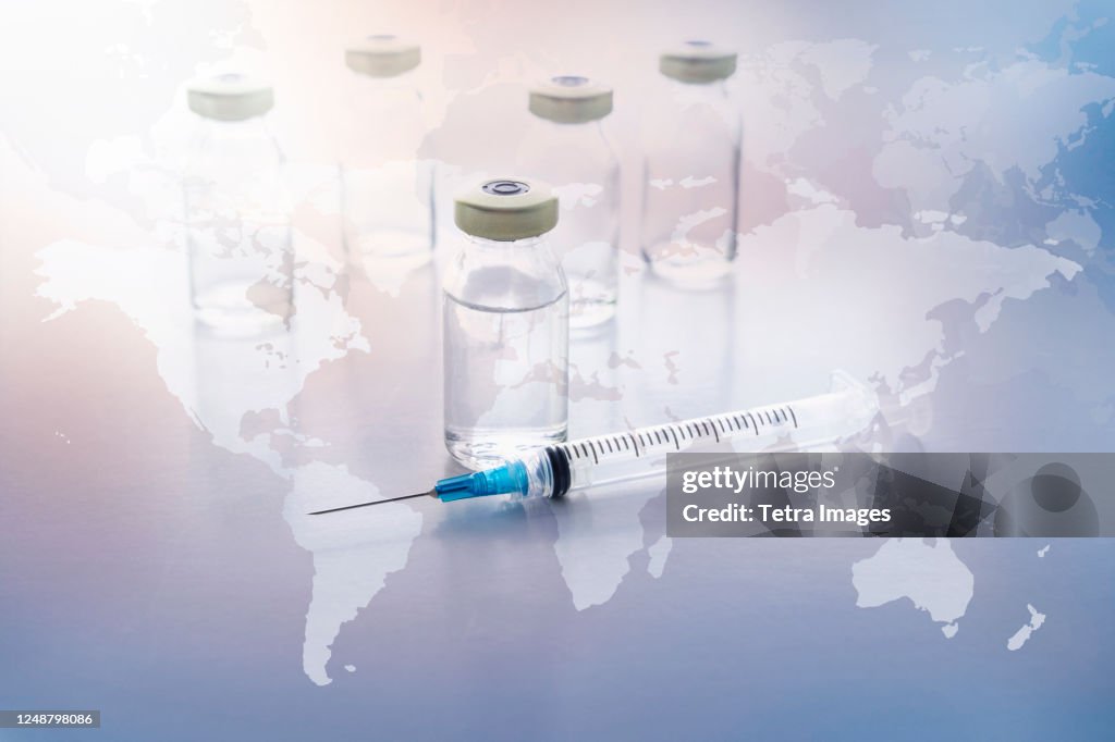 Vials and syringe with world map in background