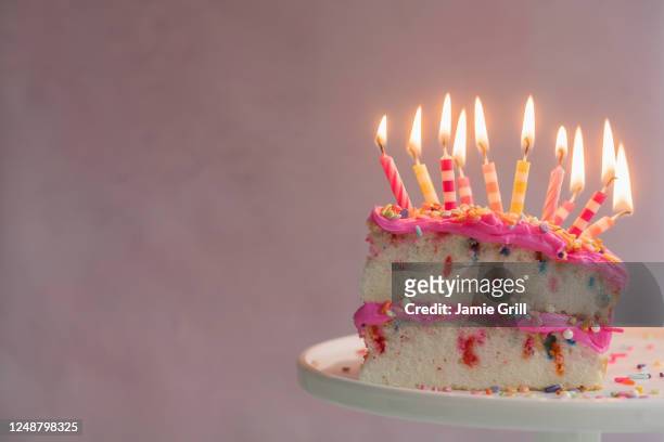 slice of birthday cake with lit candles - cake slices stock-fotos und bilder