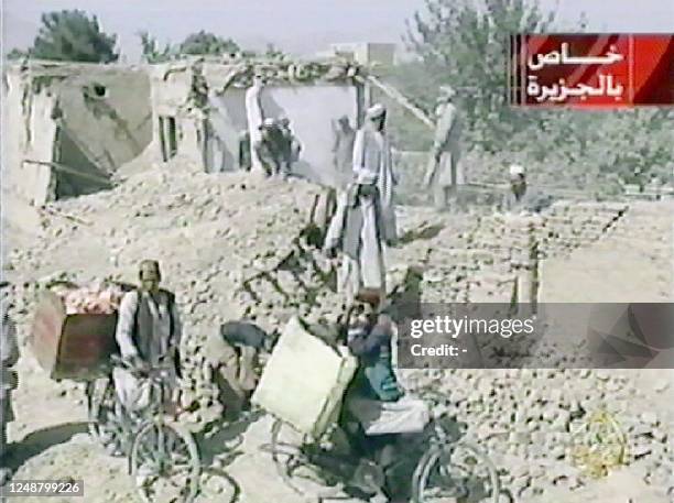 This TV grab from the Qatar-based satellite TV station al-Jazeera shows Afghanis inspecting damage in Kabul 08 October 2001 following the first night...
