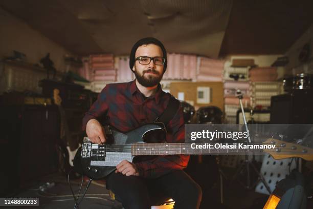 young man playing bass guitar during rehearsal in garage - musician portrait stock pictures, royalty-free photos & images